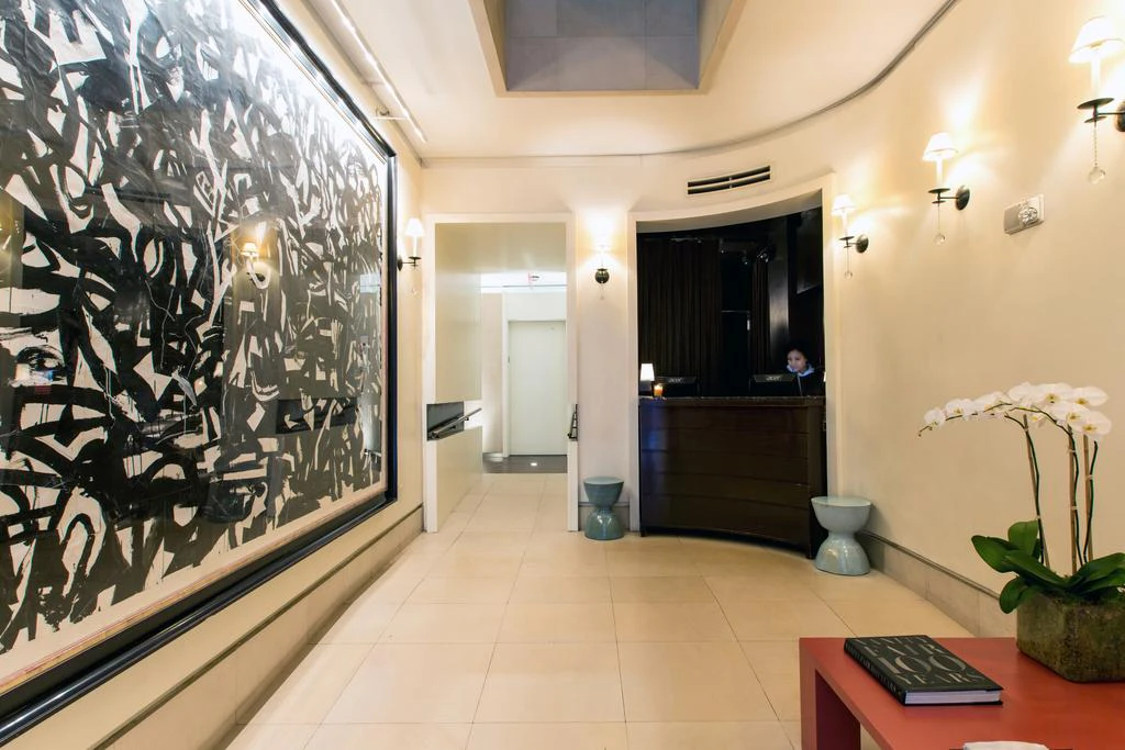 A hotel lobby with a large abstract artwork, a reception desk, and a plant.