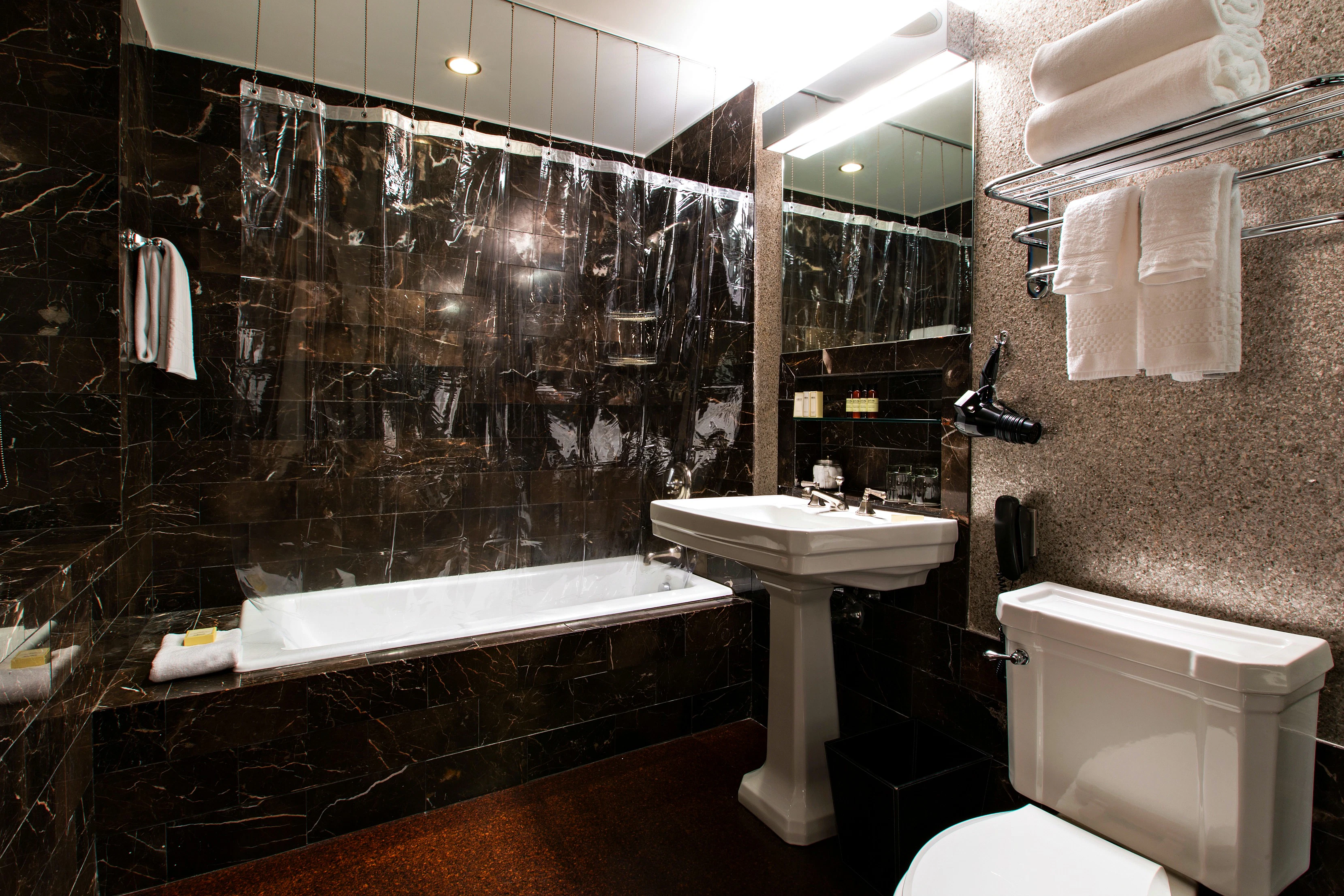 A luxurious bathroom with a bathtub, sink, toilet, and marble tiles