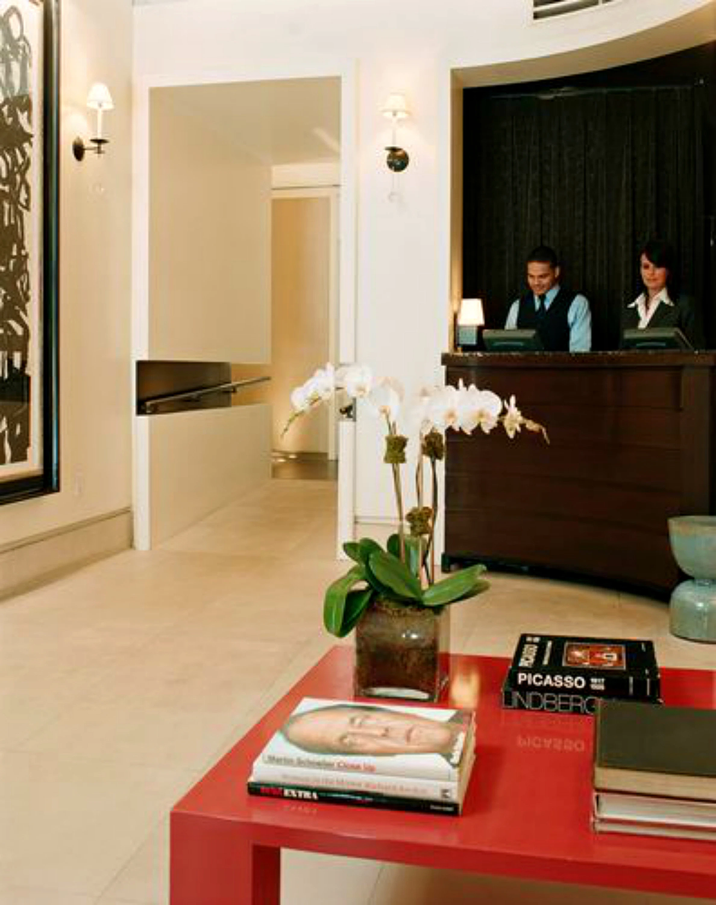 A hotel lobby with a red coffee table, white flowers, and a reception desk