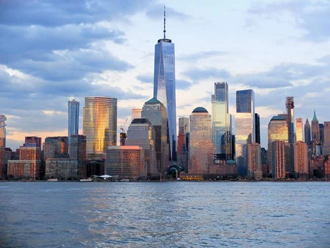 A city skyline with many skyscrapers and a body of water in the foreground.