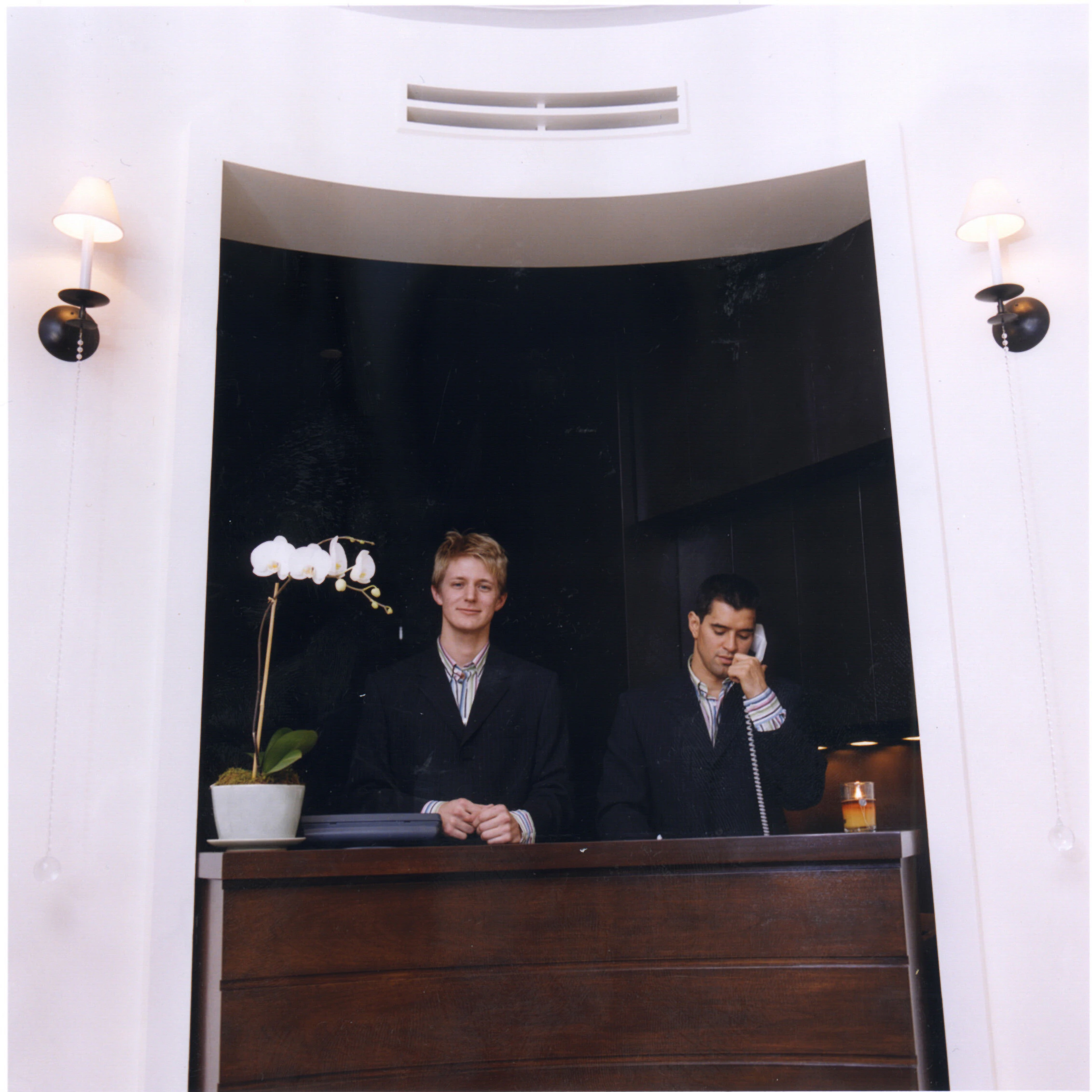 Two staff members are standing behind the front desk.
