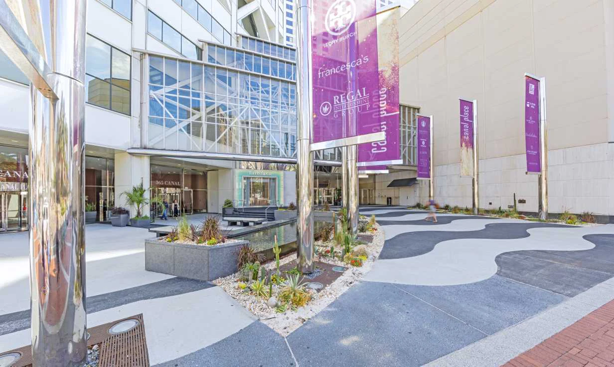 A modern building with a glass facade and purple banners in a courtyard.