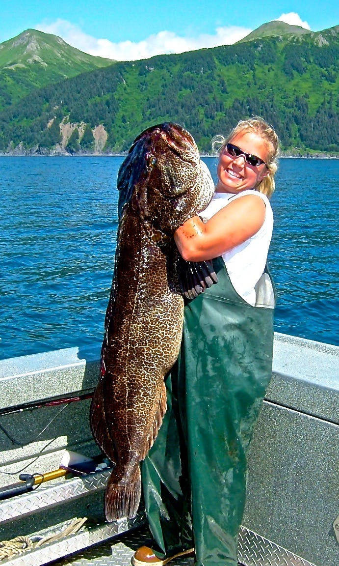 Fisherman posing with a ling cod she caught while on a alaska saltwater fishing trip with Deep Creek Fishing Club.