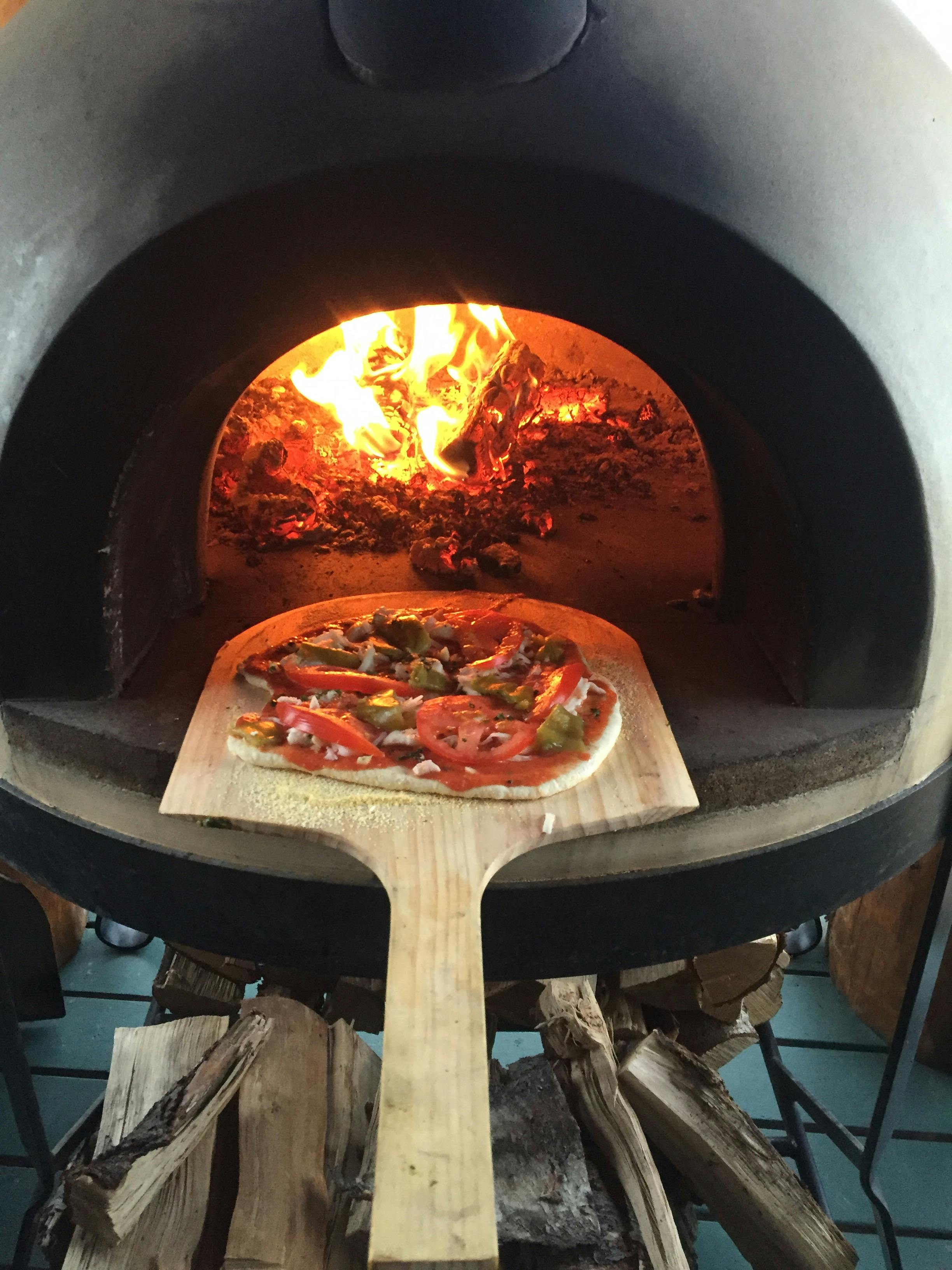 A house-made pizza on a wooden paddle ready to go in to the pizza oven at Alaska's Deep Creek Fishing Club.