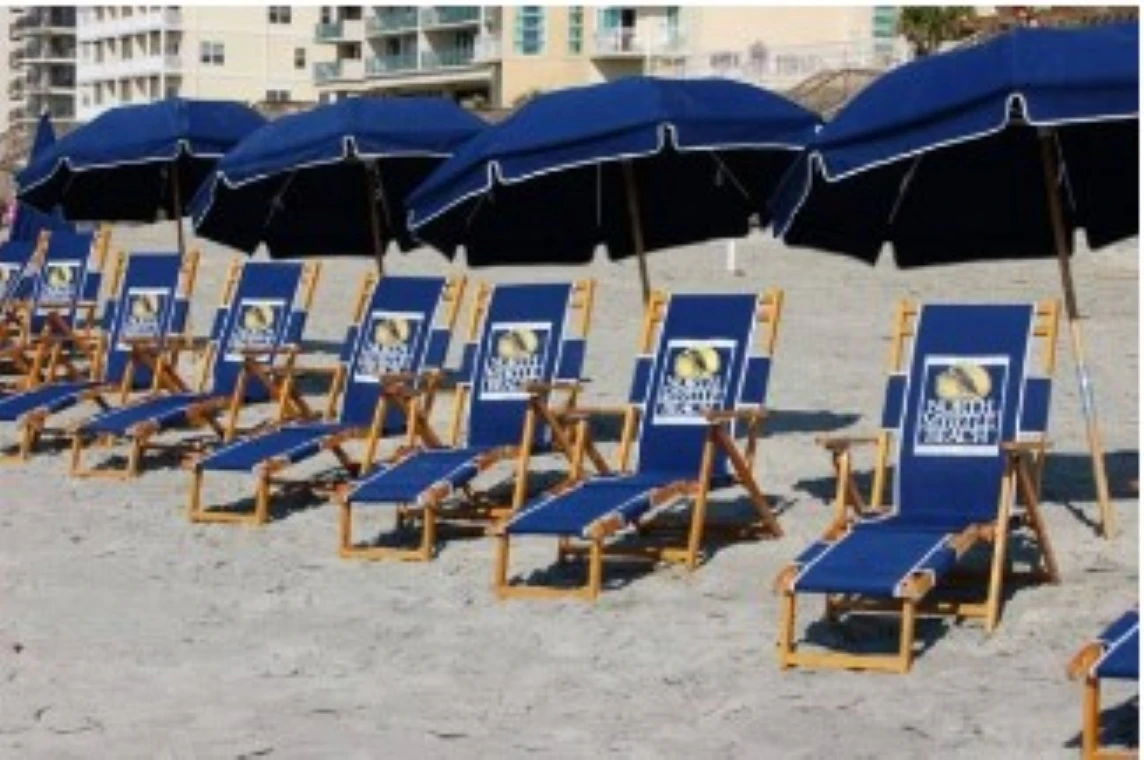 A row of blue beach chairs and umbrellas on a sandy beach.