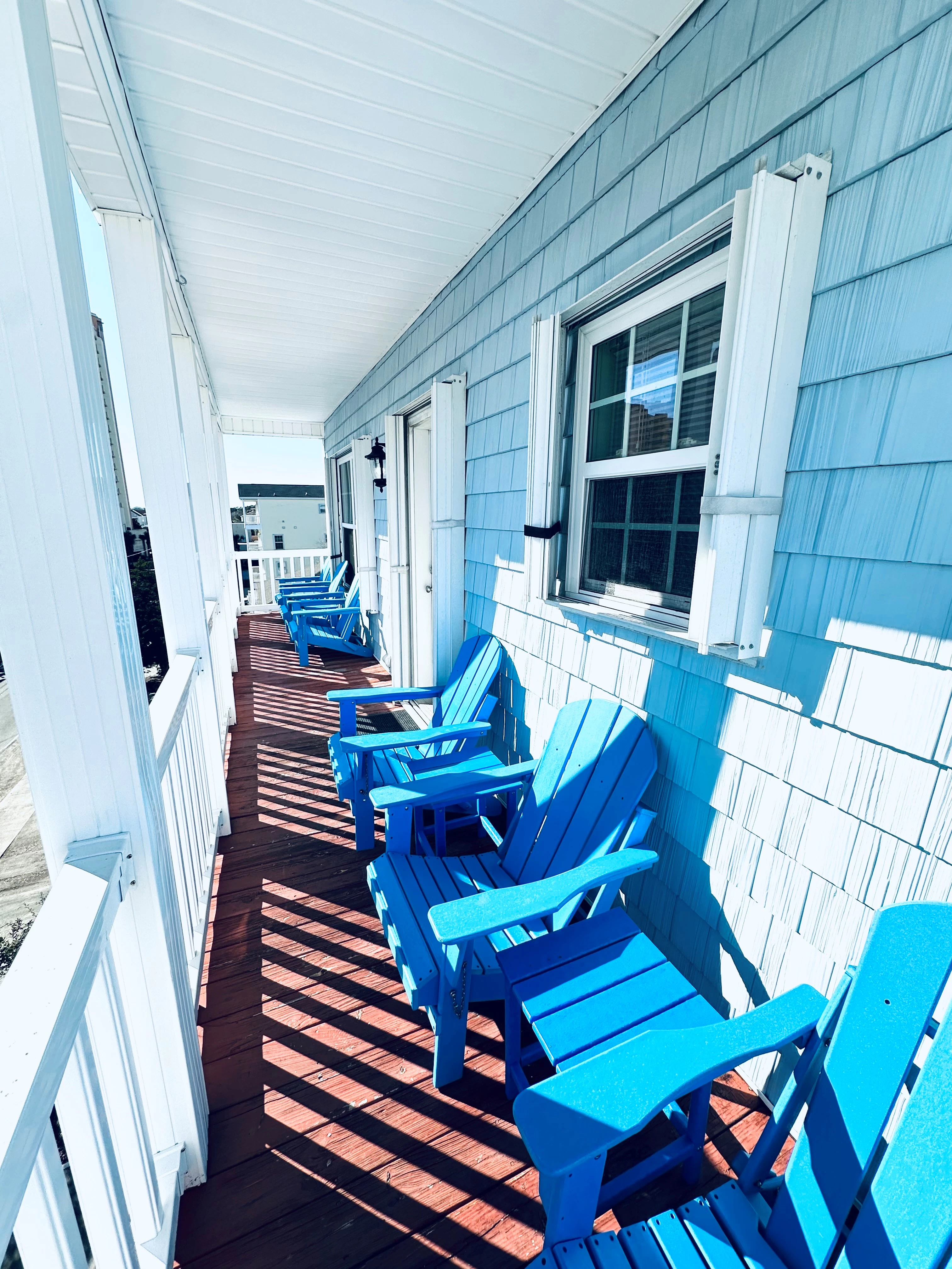 A porch with blue chairs and a wooden deck