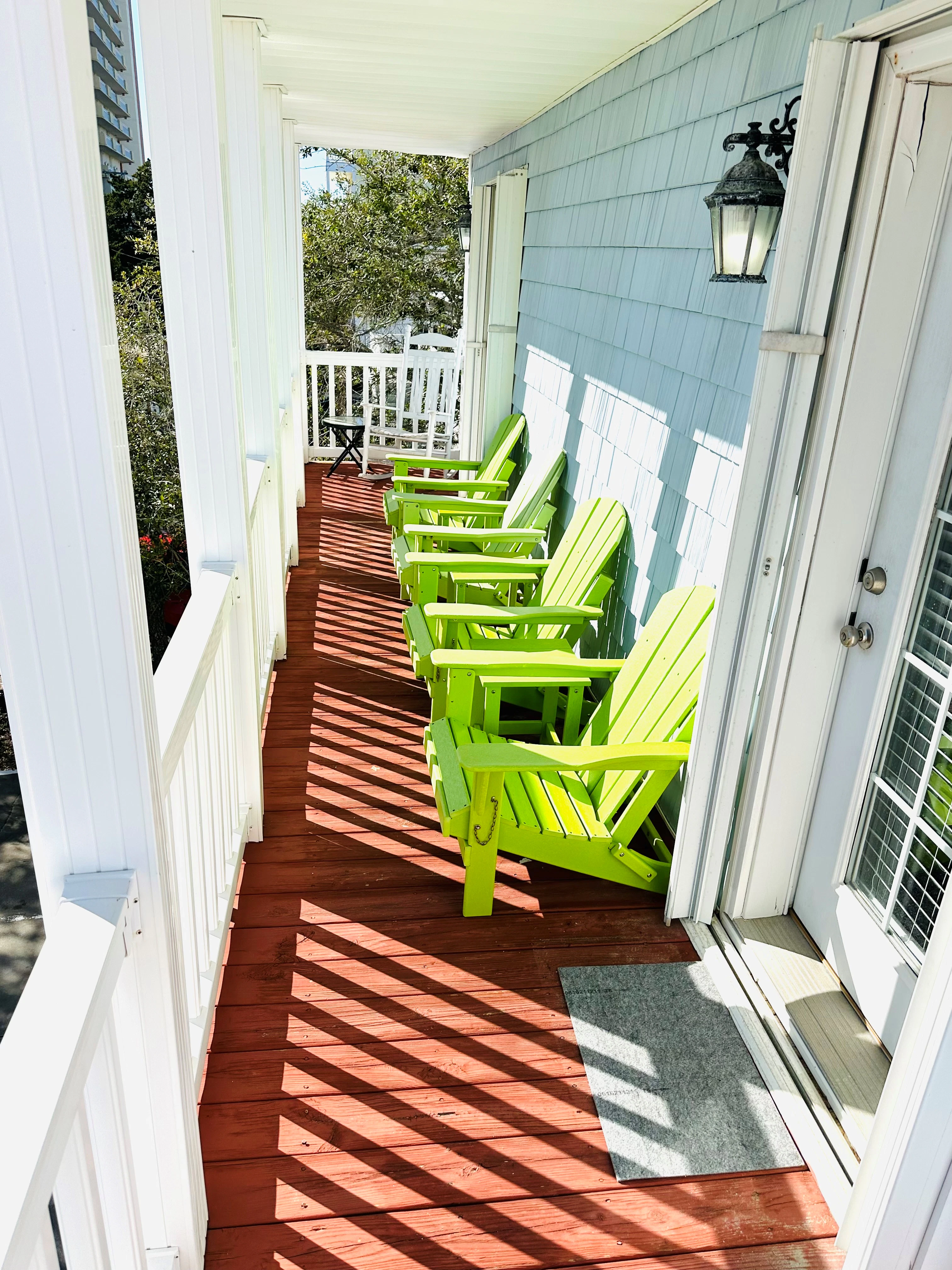 A porch with green chairs and white railing