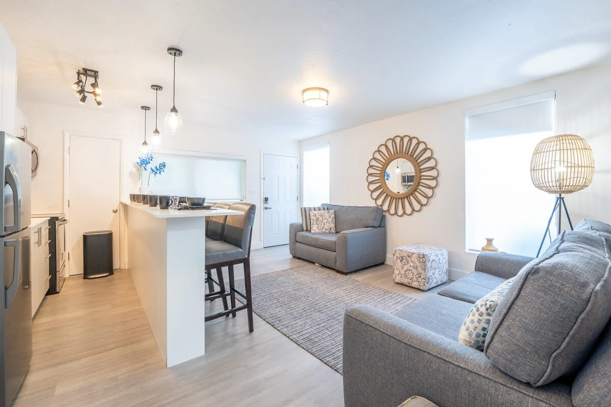 A wide view of a living room with a kitchenette, sofa, armchair, and decor.