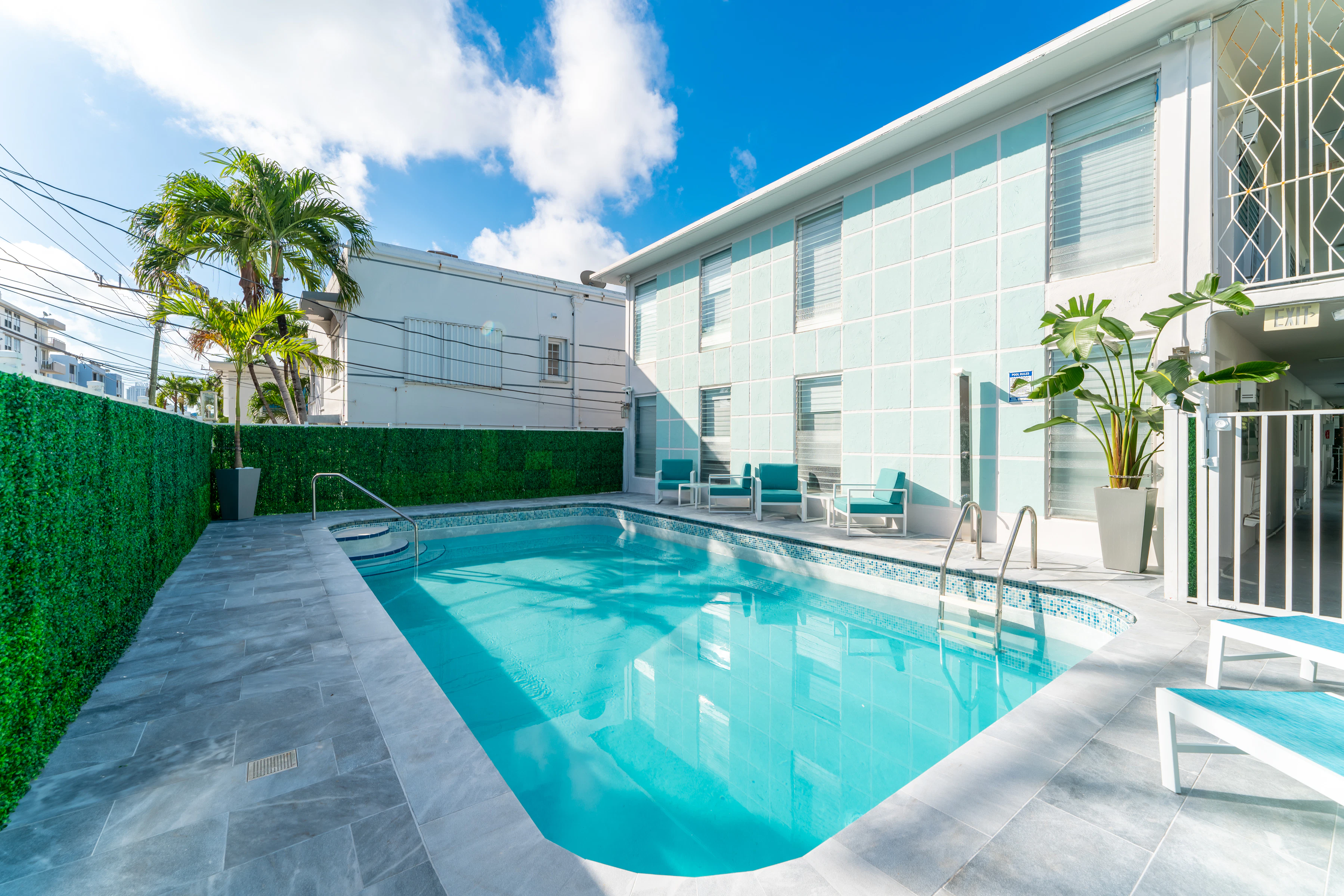 A swimming pool with lounge chairs and a hedge in a tropical setting