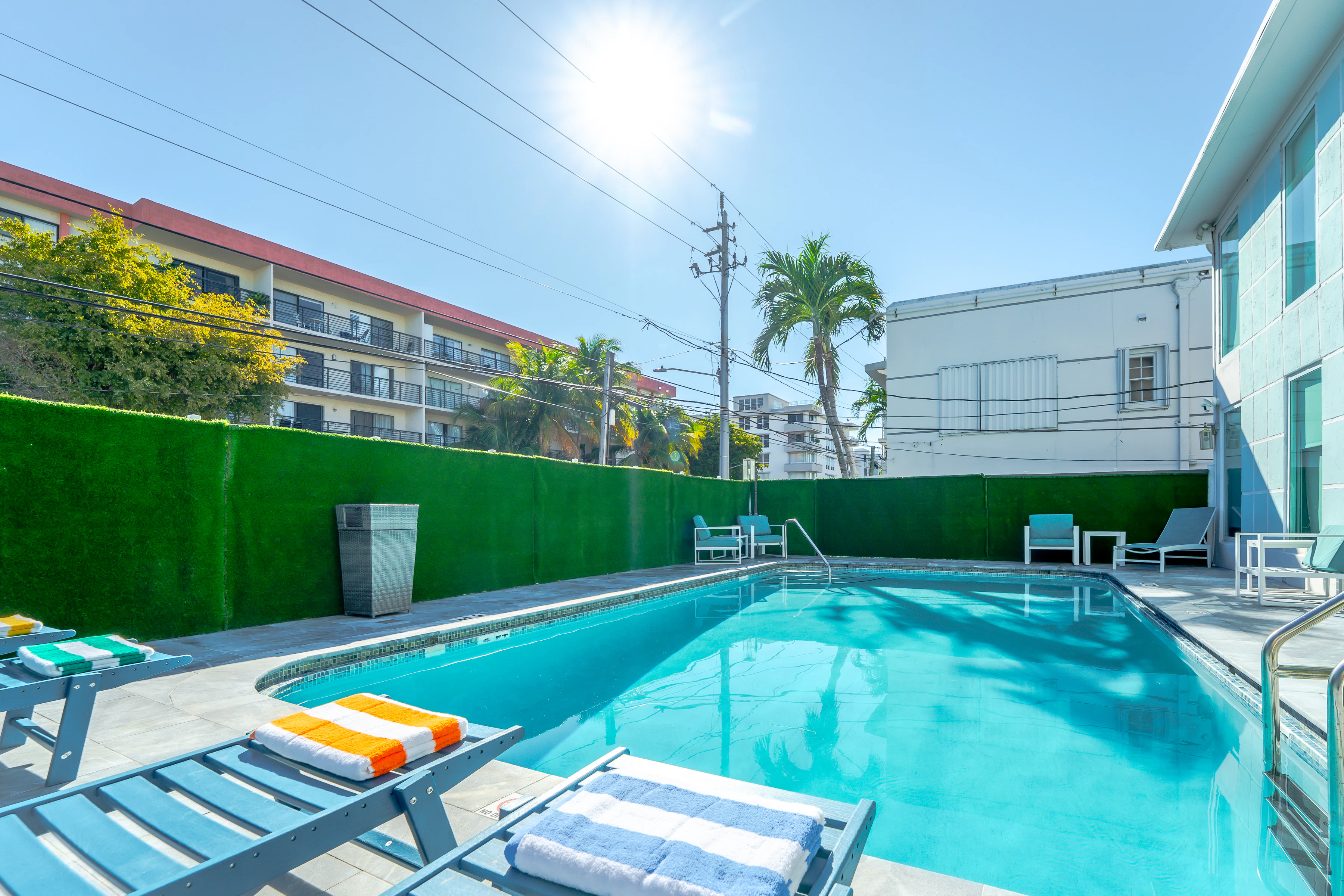 A swimming pool with lounge chairs and towels on a sunny day.