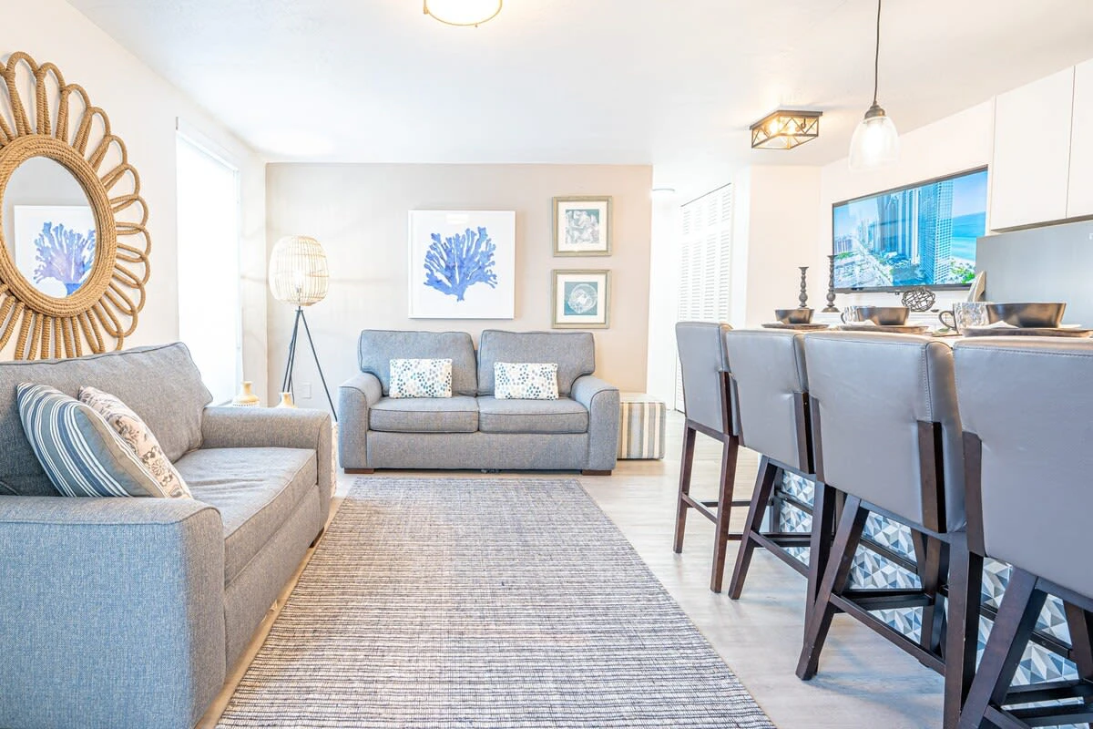 A bright and airy living room with a kitchenette, sofa, and dining area.