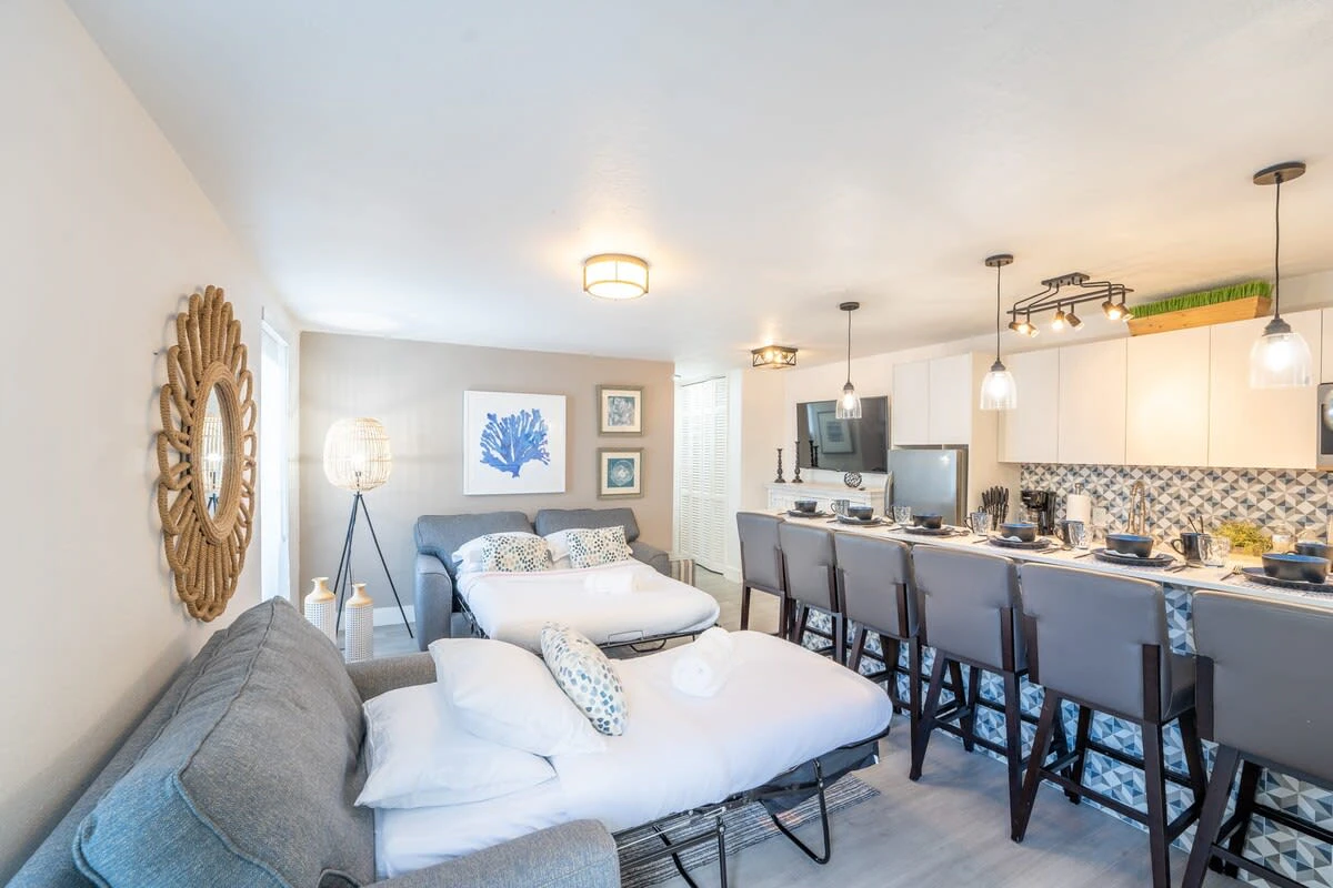 A wide view of a compact living space with a sofa bed, kitchenette, and dining area.