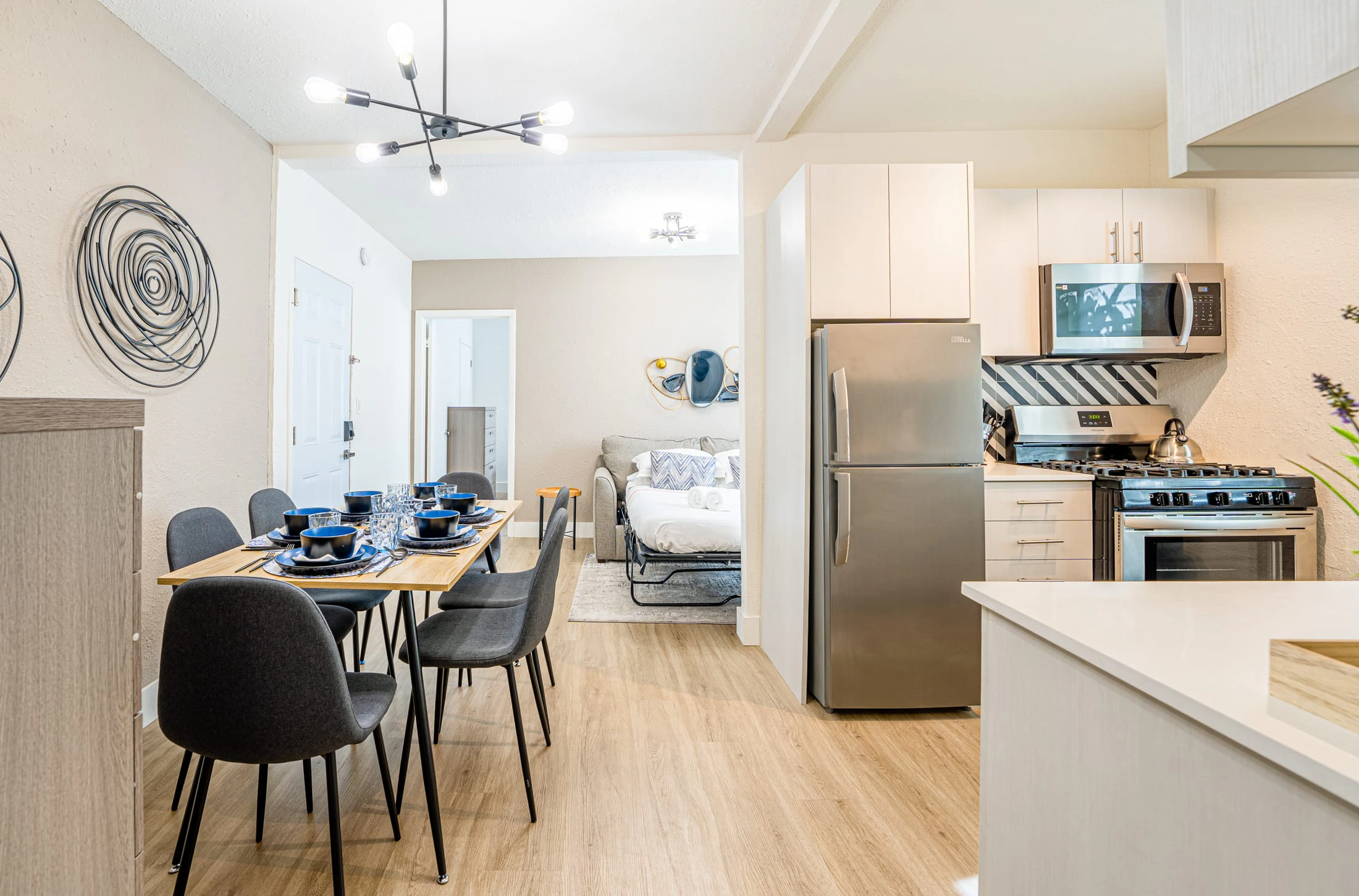 A modern open-plan kitchen and dining area with a Murphy bed in the background.