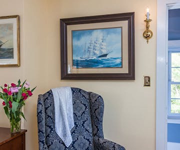 Sitting chair with beautiful sailing painting on the wall.