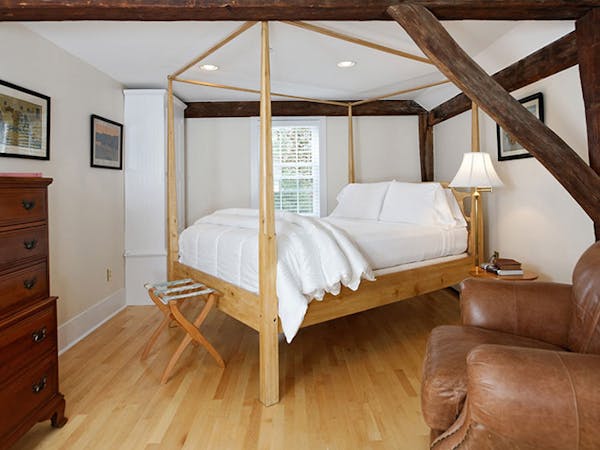 Four-post bed in clean, bright room with exposed brick.