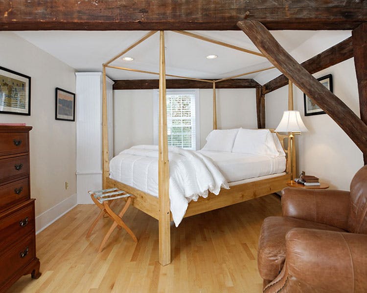 Four-post bed in clean, bright room with exposed brick.