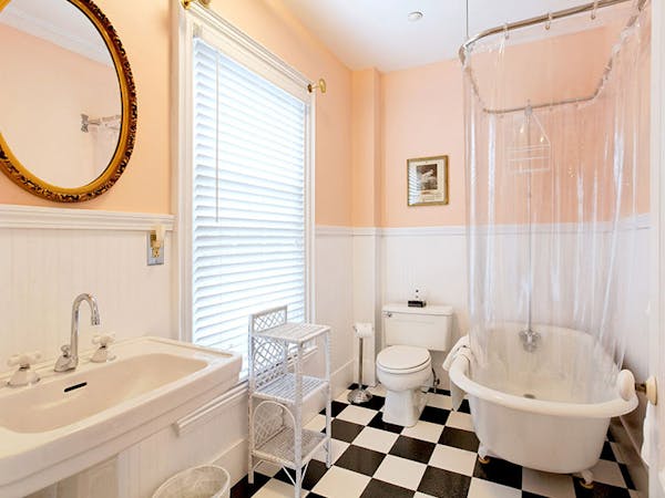 Bathroom with claw-foot tub, pedestal sink, and black and white checked floor.