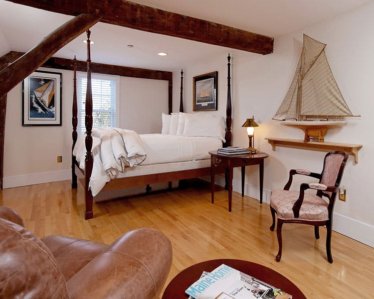 America's Cup room interior with 4-poster bed, exposed wooden beams, decorative chair, and decorative sail boat.