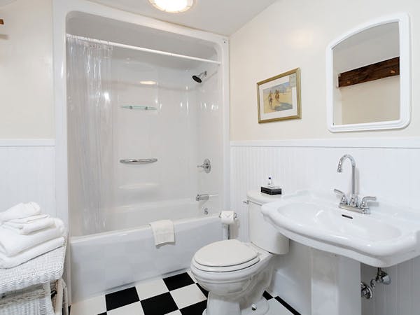 Clean, white bathroom with pedestal sink and black and white checked floor.