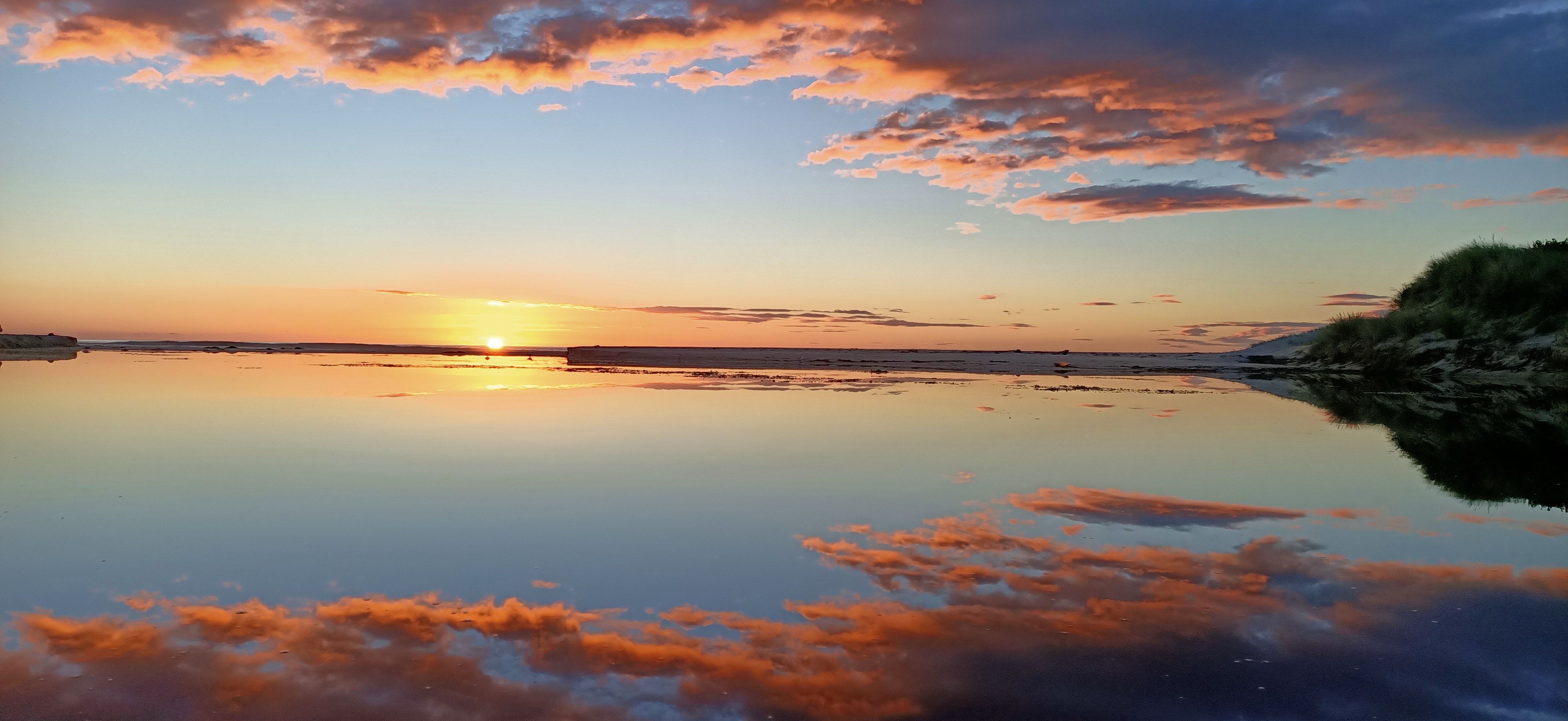 Orange dawn reflected in still water.
