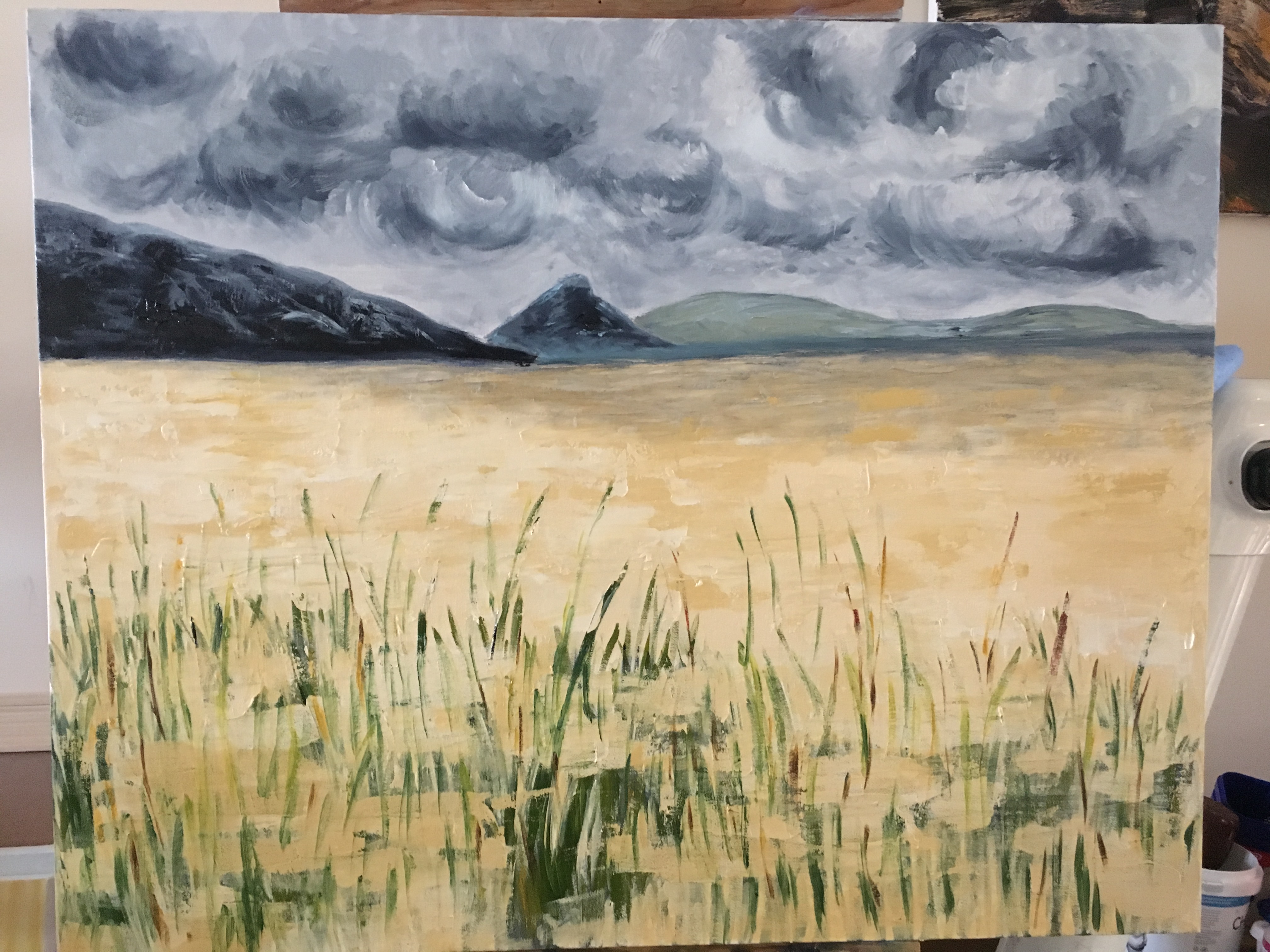 Detail of a painting of storm clouds above a wheatfield, with hills in the background.