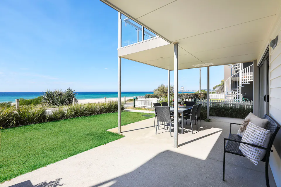 Shaded ground-floor terrace and lawn looking out to the ocean at Sandbox Apartments