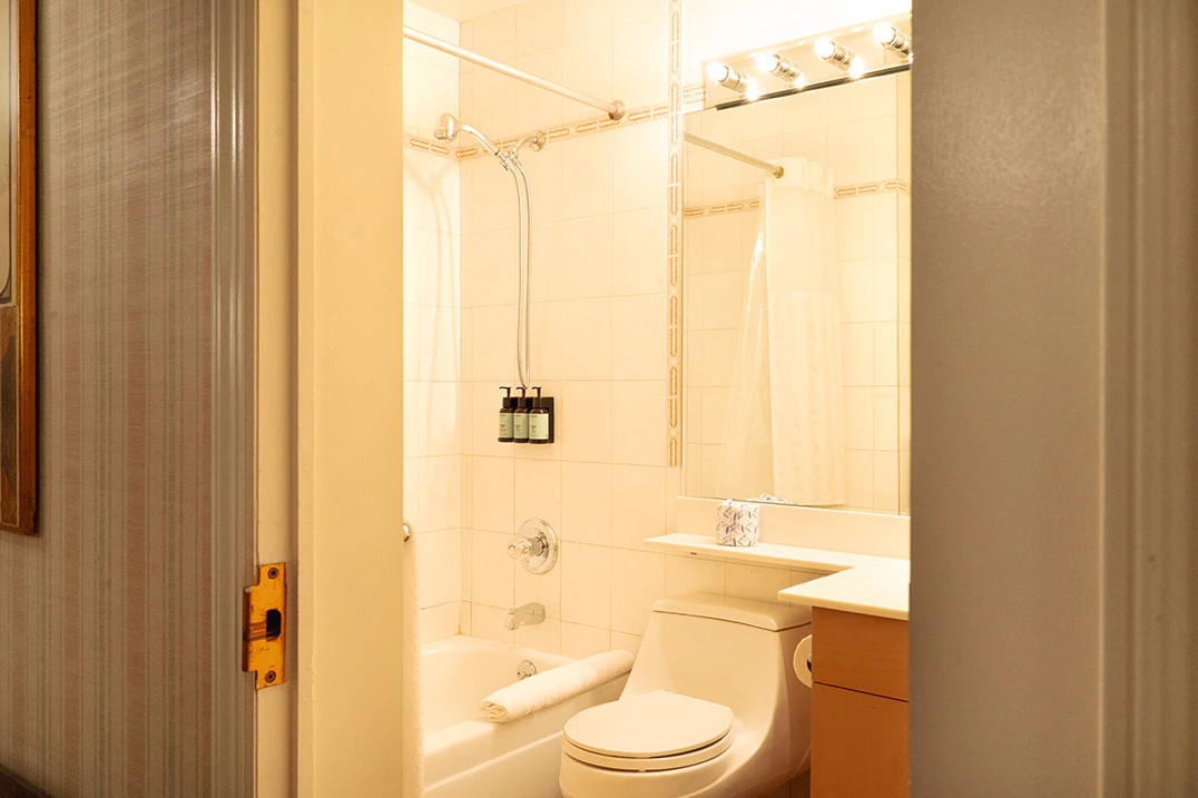 A bathroom with a toilet, shower, bathtub, mirror, and sink.