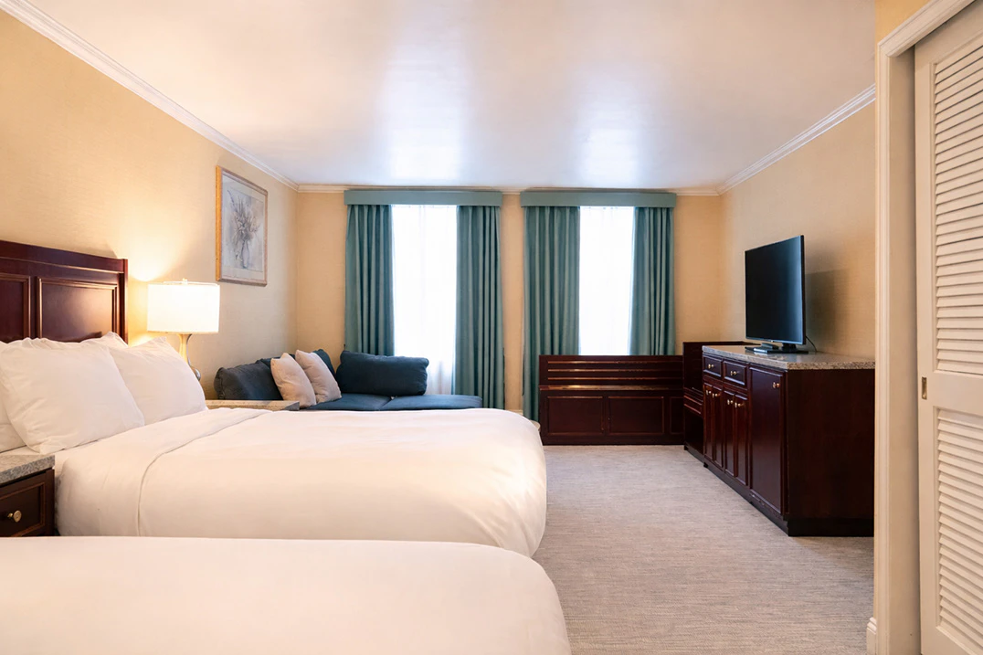A hotel room with two beds, a TV, and a window