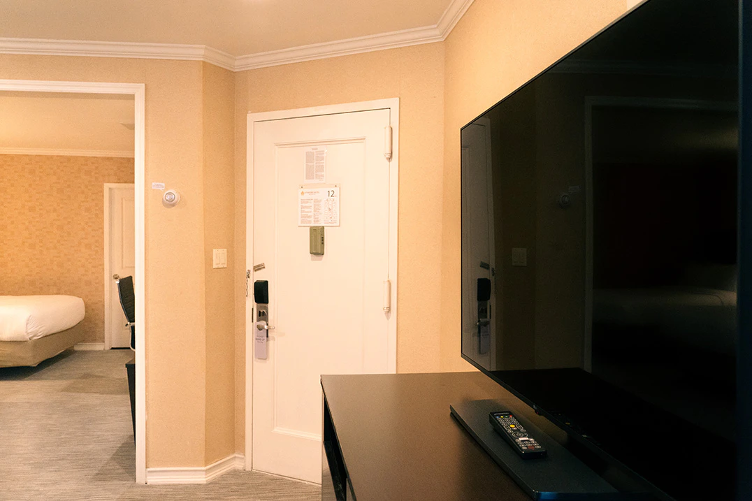 A hotel room with a TV on a desk and a door leading to another room
