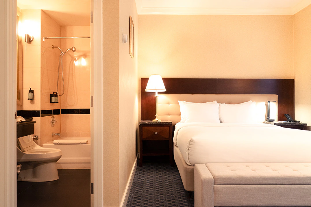 A hotel room with a bed, nightstand, and bathroom