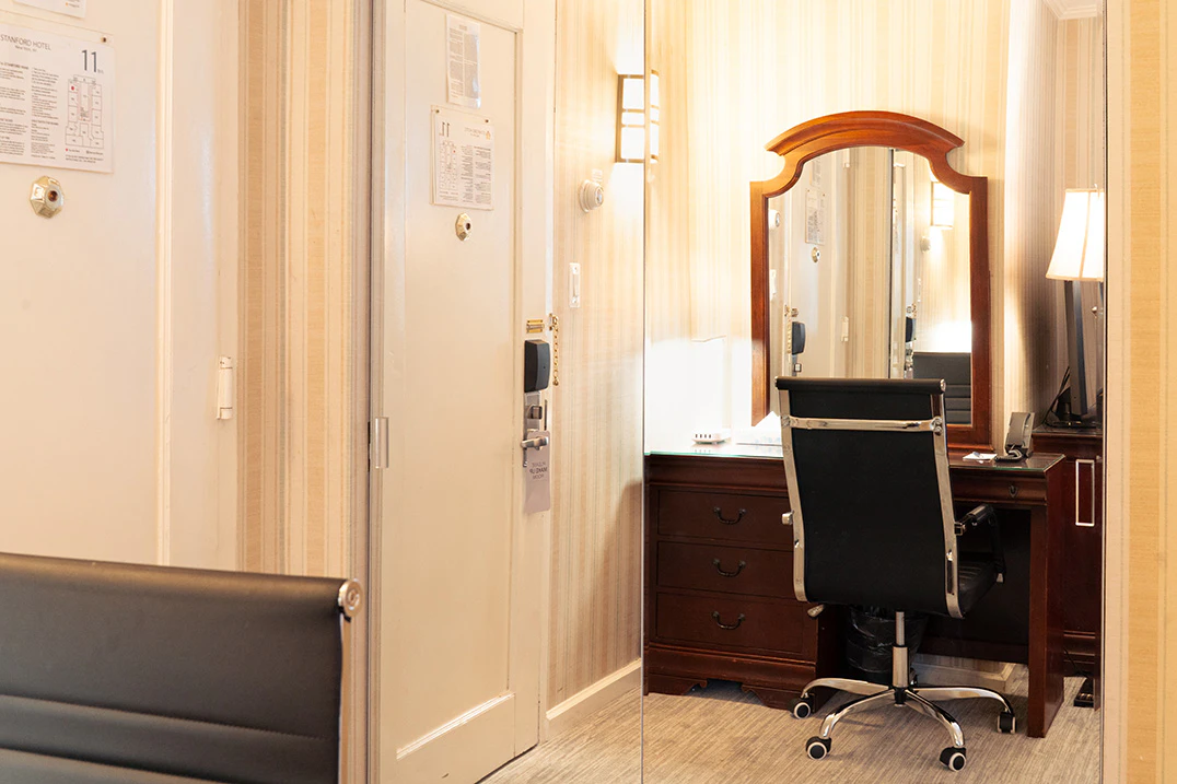 A hotel room with a desk, chair, and mirror