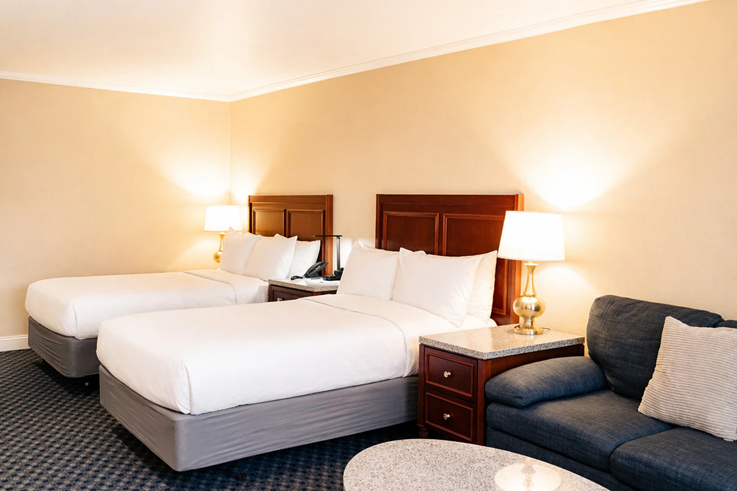 A hotel room with two beds, a sofa, and a coffee table.
