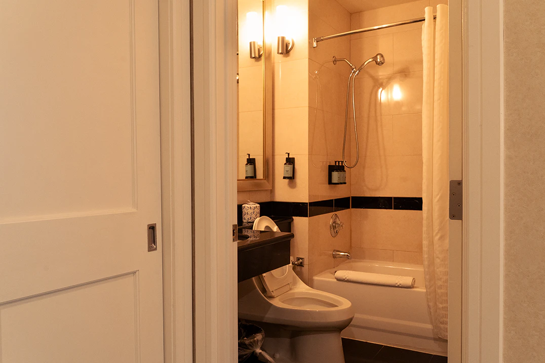 A bathroom with a toilet, shower, bathtub, mirror, and soap dispenser.