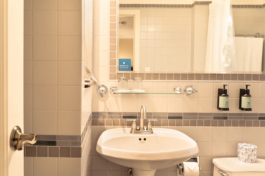 A bathroom sink area with a mirror, toilet, and tiled walls.