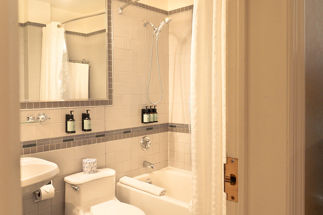 A clean bathroom with a toilet, shower, bathtub, mirror, and sink.