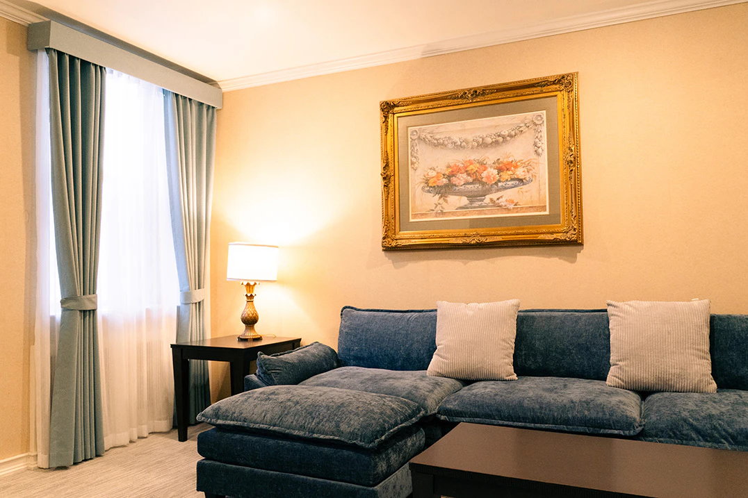 A living room with a blue sofa, coffee table, end table with lamp, and artwork on the wall.