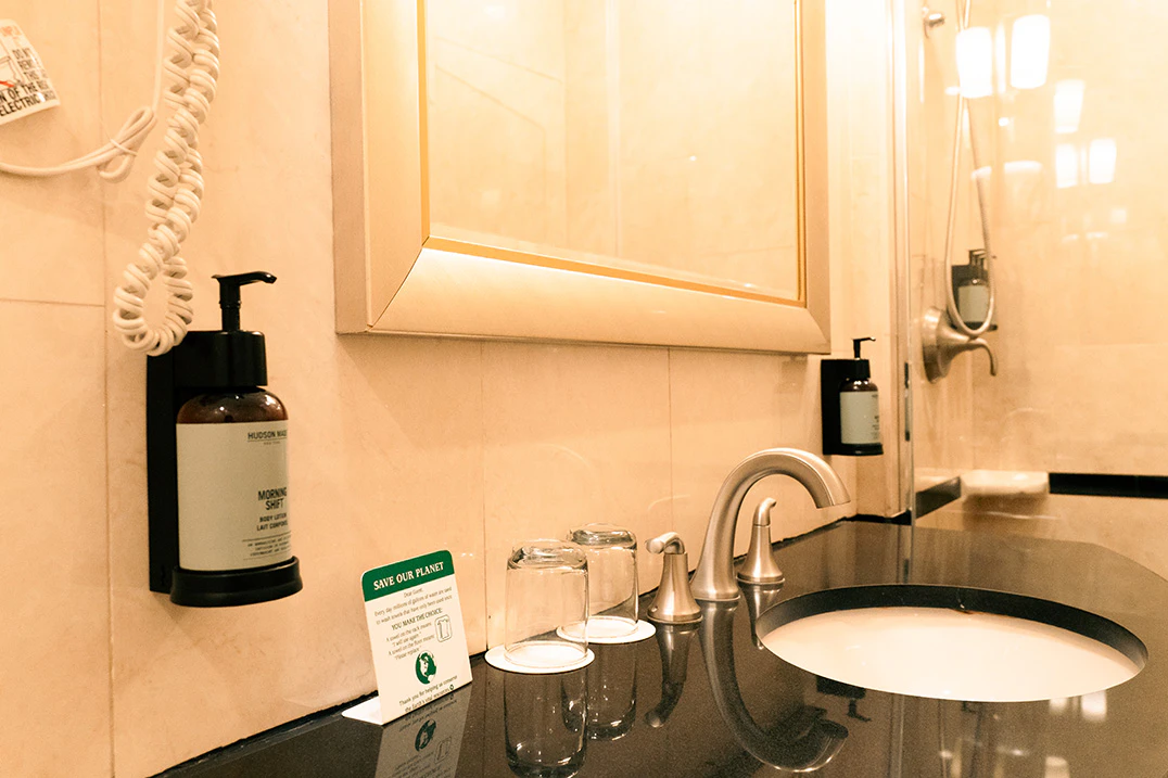 A bathroom sink with a black countertop, silver faucet, and glass cups