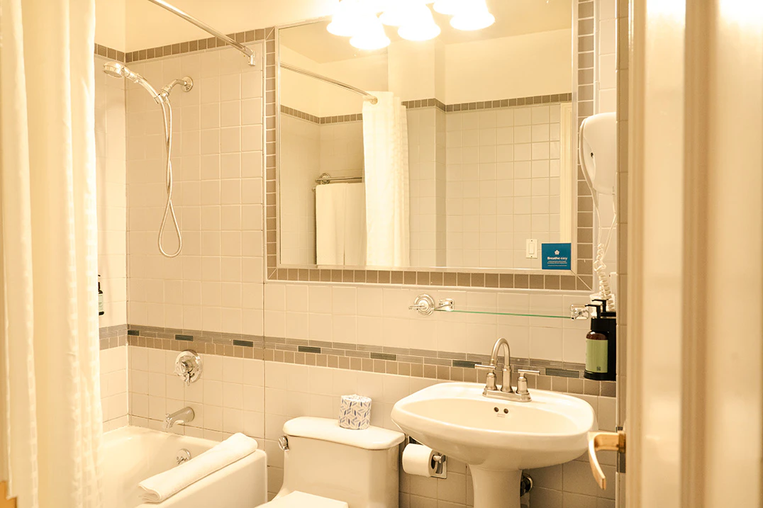 A clean bathroom with tiled walls, a bathtub, toilet, lavatory, and mirror.