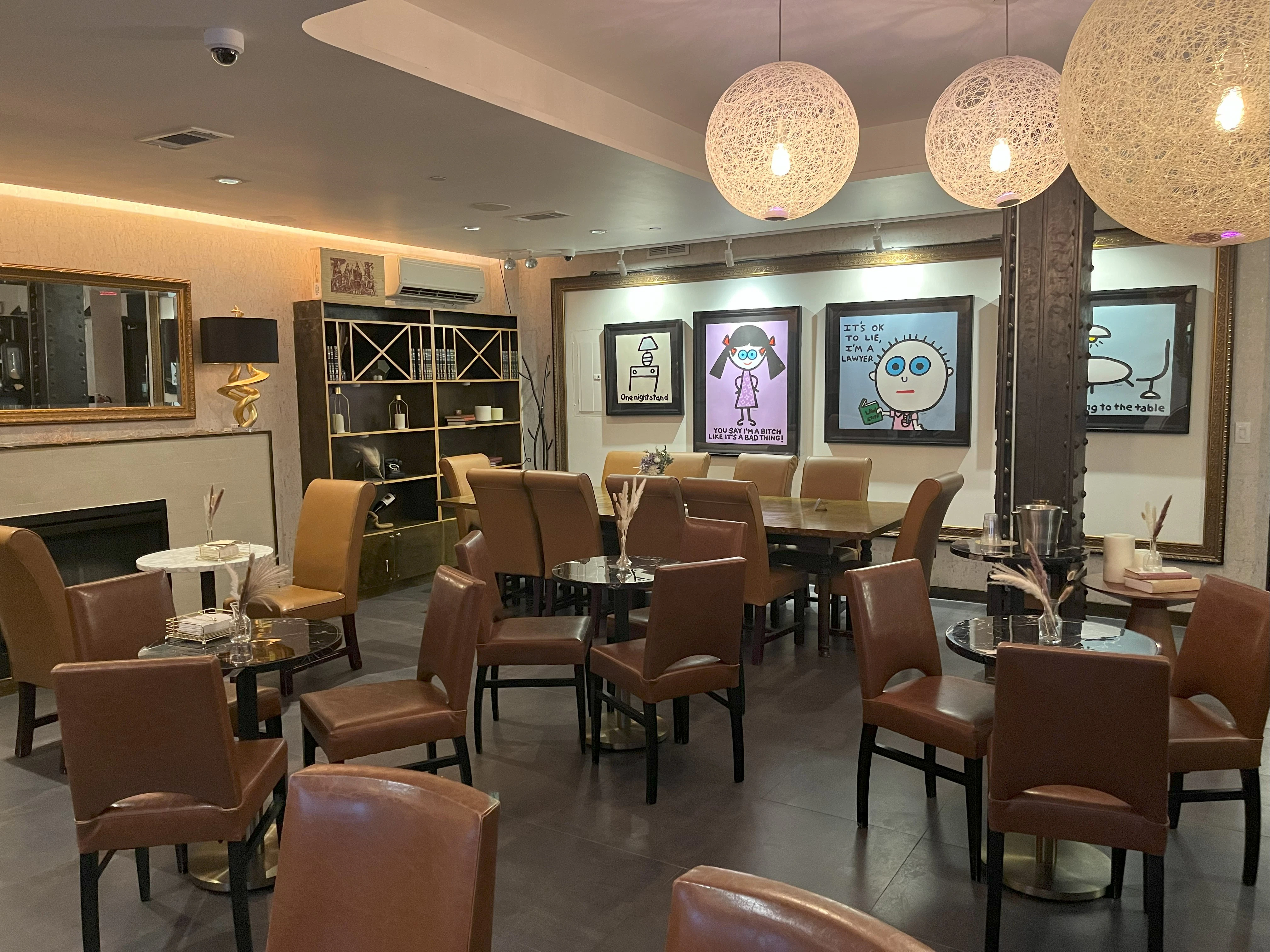 A lounge area with leather chairs, round tables, and artwork on the walls.