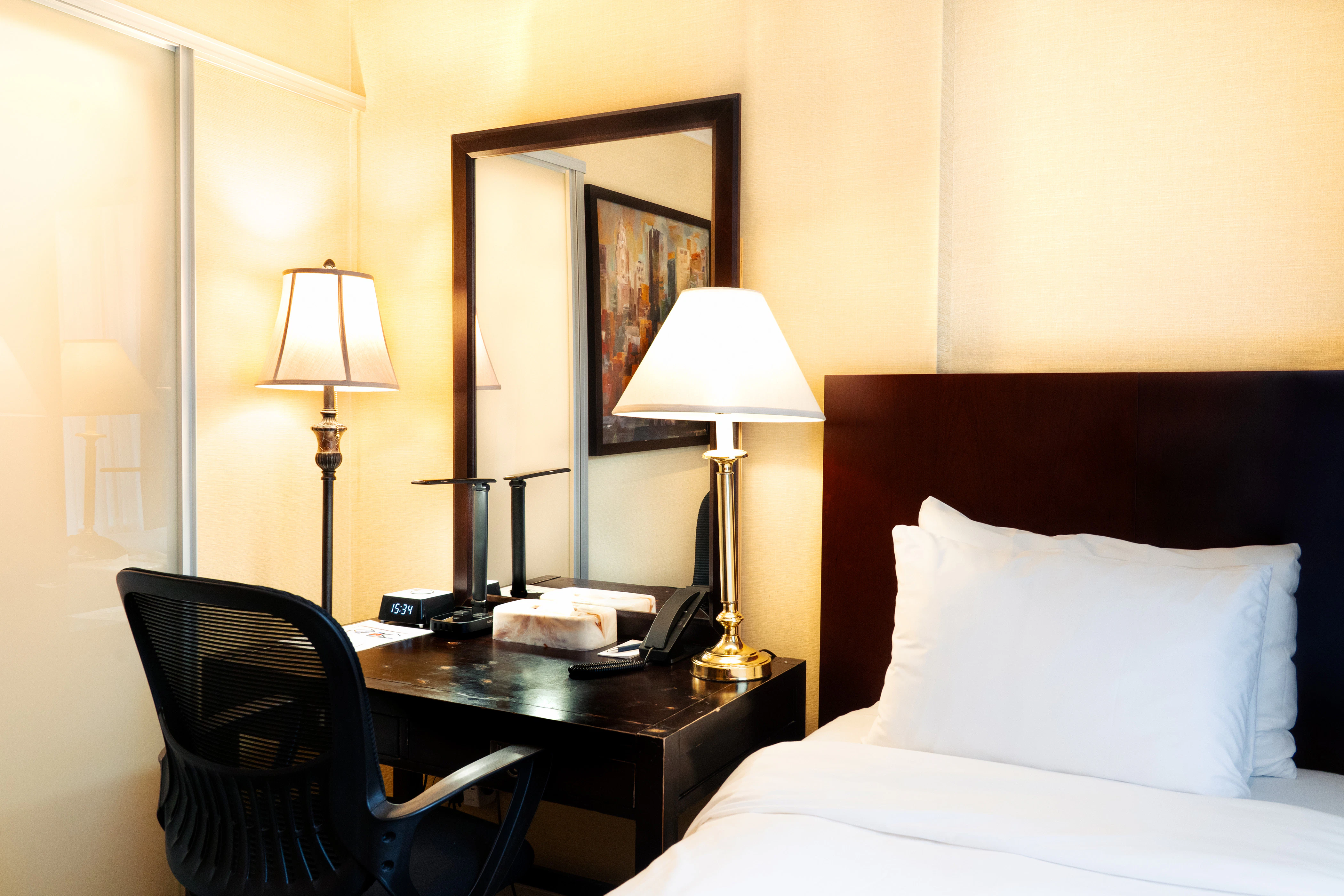 A hotel room with a single bed, desk, and chair