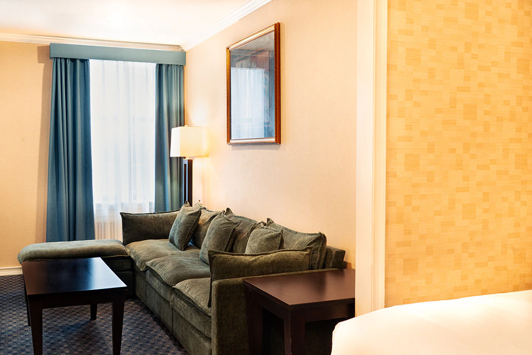 A wide view of a hotel room with a green sofa, coffee table, and lamp.