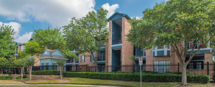 A three-story brick building with balconies and a fenced yard