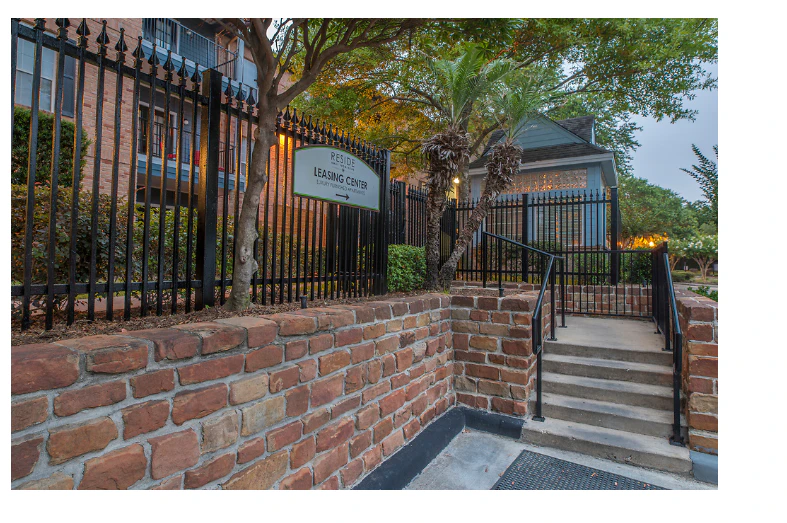 A brick wall with a black gate and staircase leading to a building