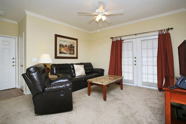 A furnished living area with a sofa, recliner, coffee table, and TV stand.