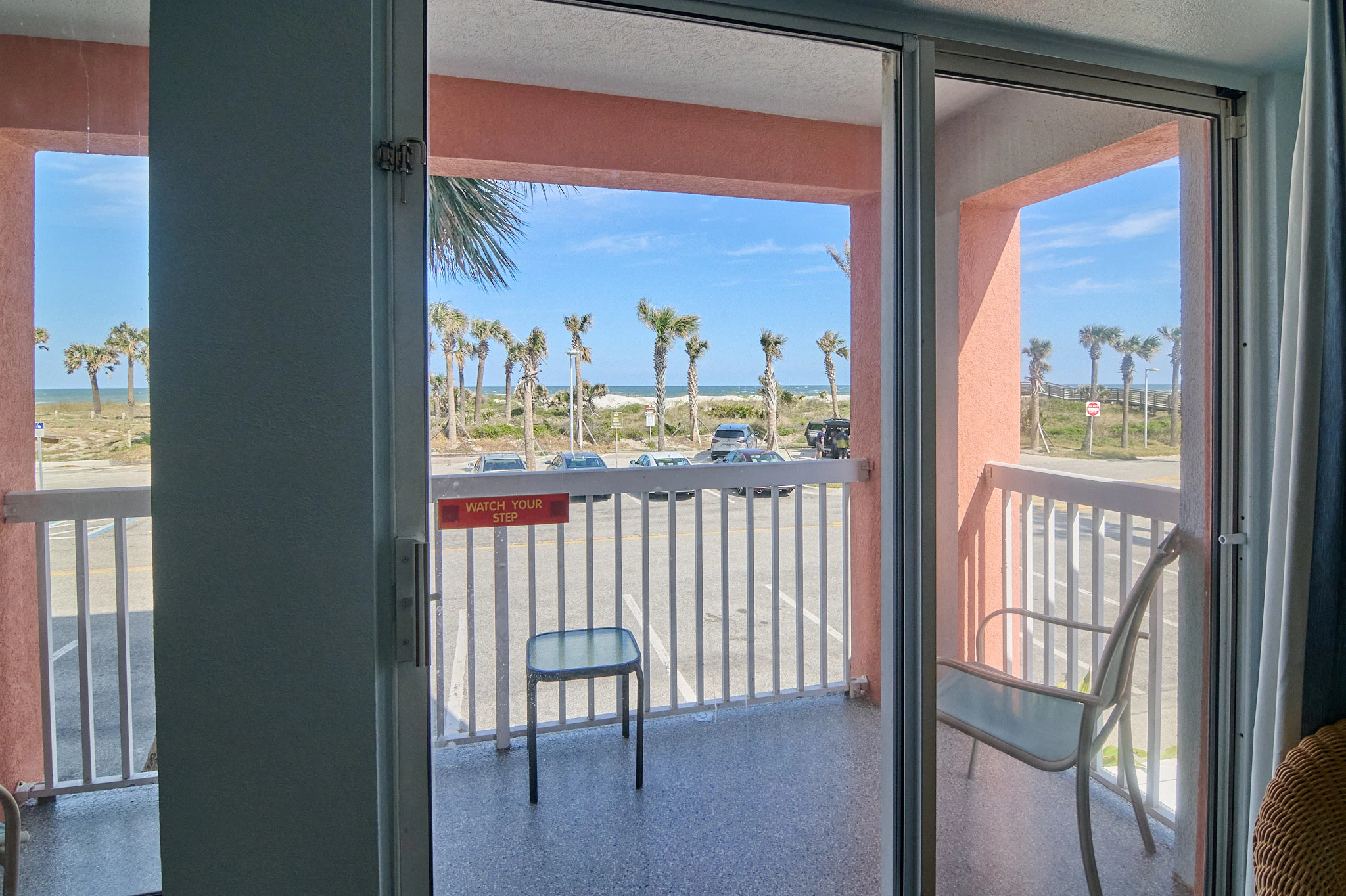 A balcony with a view of the parking lot and ocean