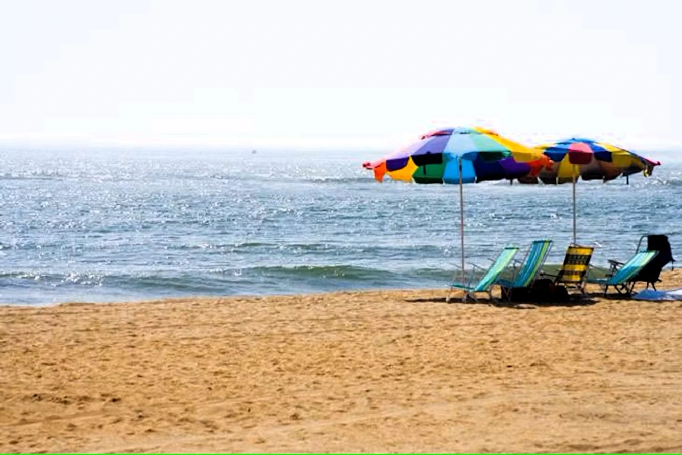 A beach scene with a colorful umbrella and chairs.