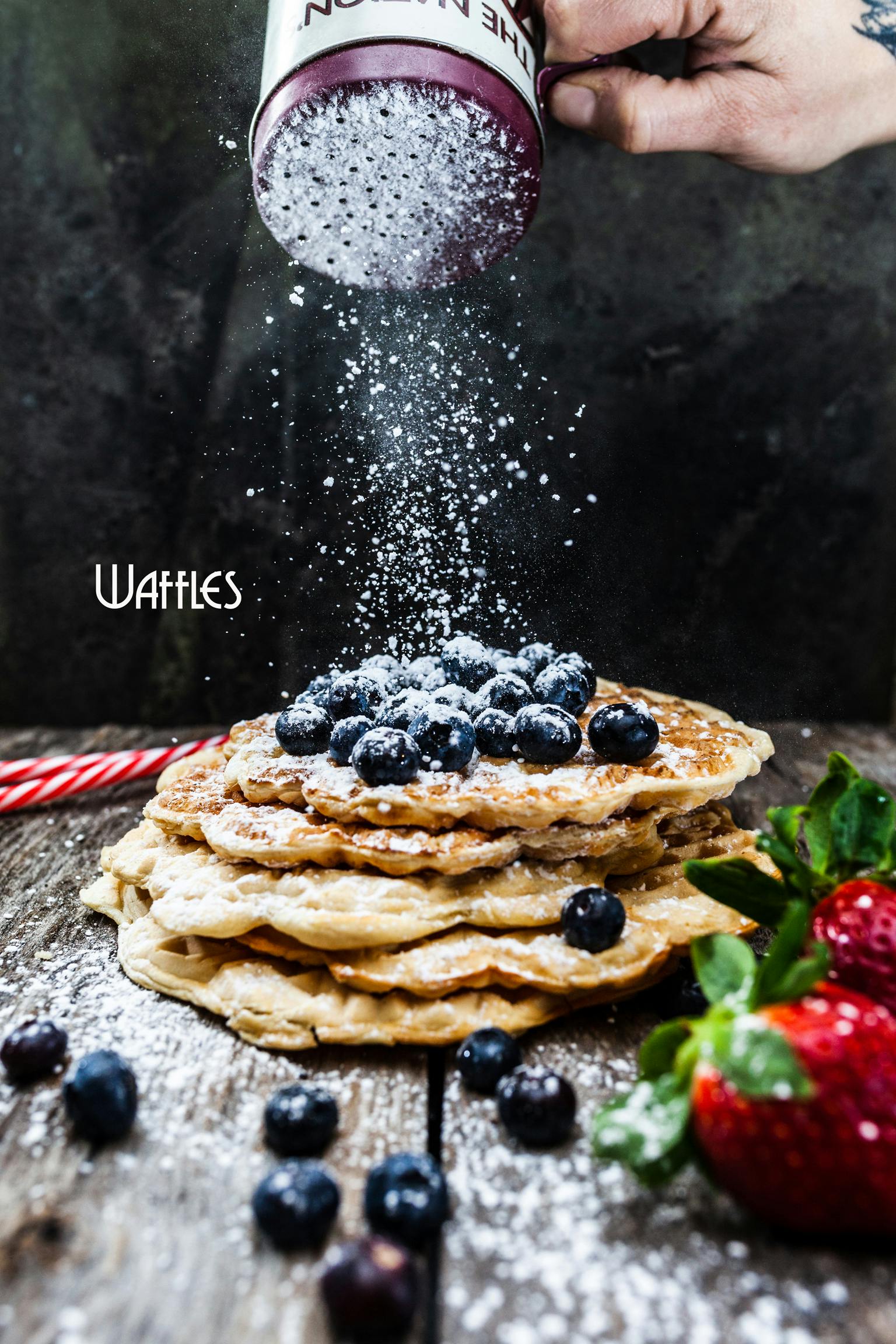 freshly prepared waffles with blueberries as topping, coated by icing sugar
