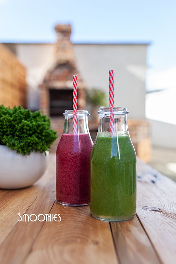 smoothies red and green with a straw on a wooden table