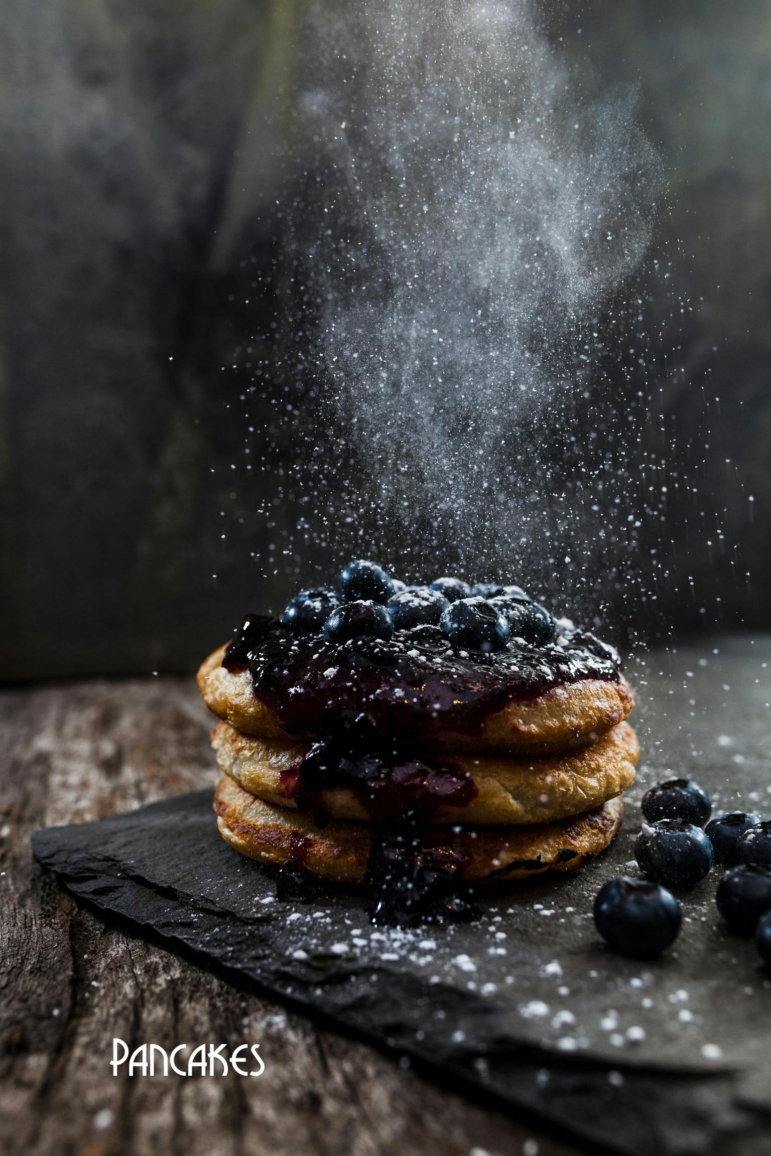 Handmade pancakes with blueberry sauce and fresh blueberries, coated by icing sugar