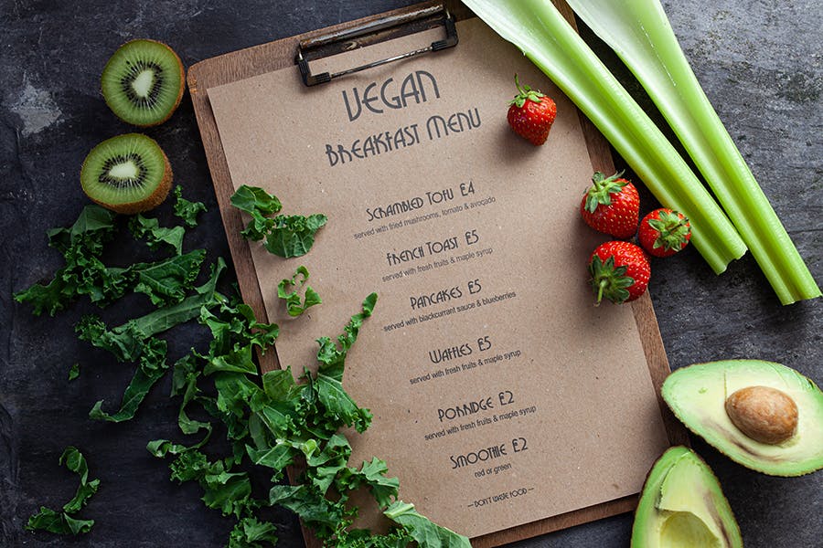 Vegan breakfast menu surrounded by vegetables and fruits